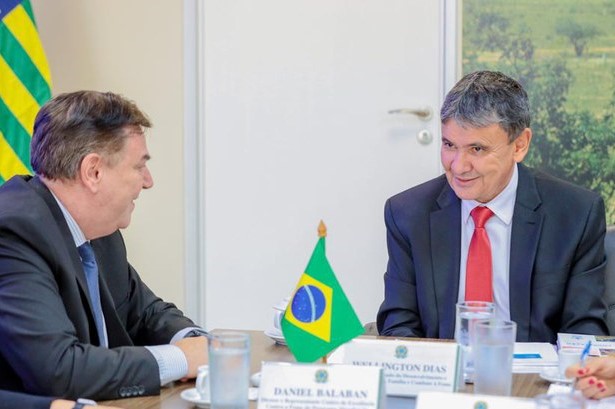 A foto mostra o Diretor do Centro de Excelência contra a Fome do WFP no Brasil, Daniel Balaban, um homem branco que veste um terno preto, à esquerda. No canto direito da foto, está o Ministro de Desenvolvimento Social, Wellington Dias, um homem branco de cabelos escuros que usa um terno preto com uma camisa social branca e uma gravata vermelha.