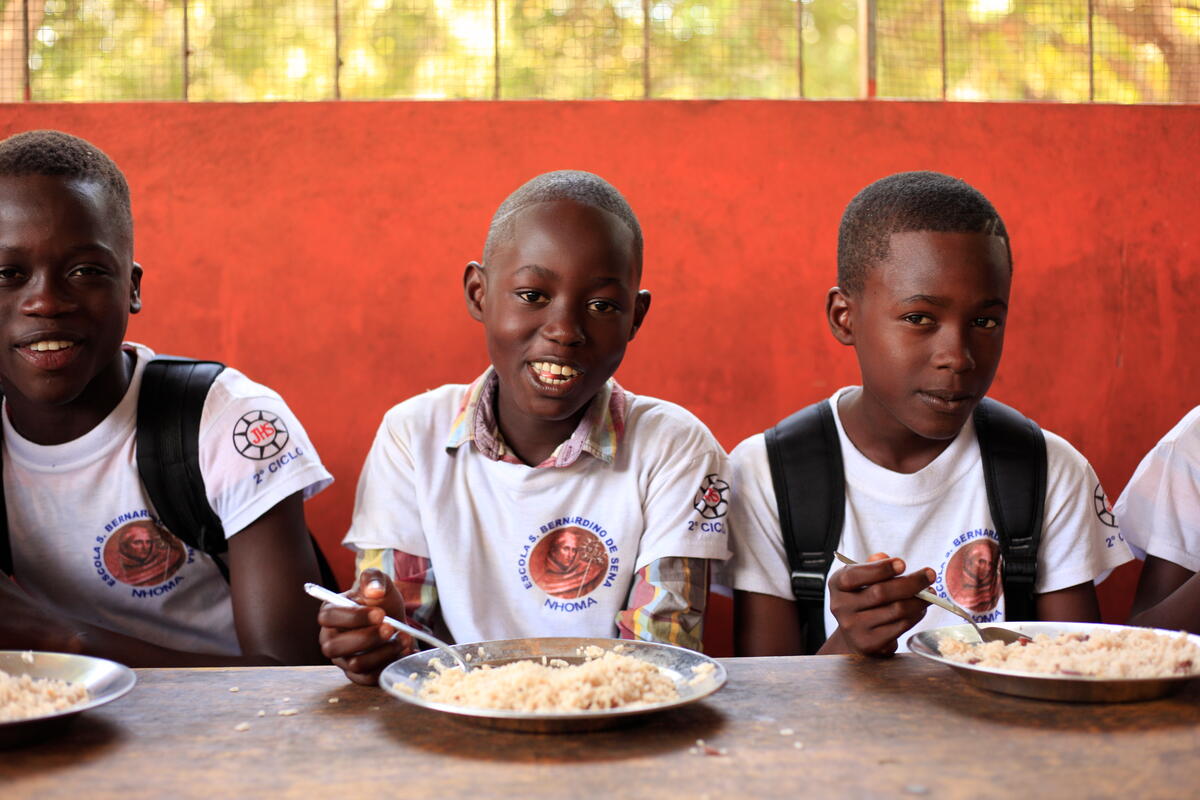 meninos negros recebendo refeições quentes do Programa de Alimentação Escolar em Guiné-Bissau 