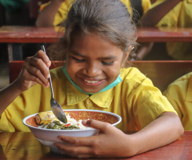 Uma aluna da Escola Filial Básica (EBF) Leilaus, no Timor Leste, desfrutando de sua refeição escolar durante o intervalo do almoço.