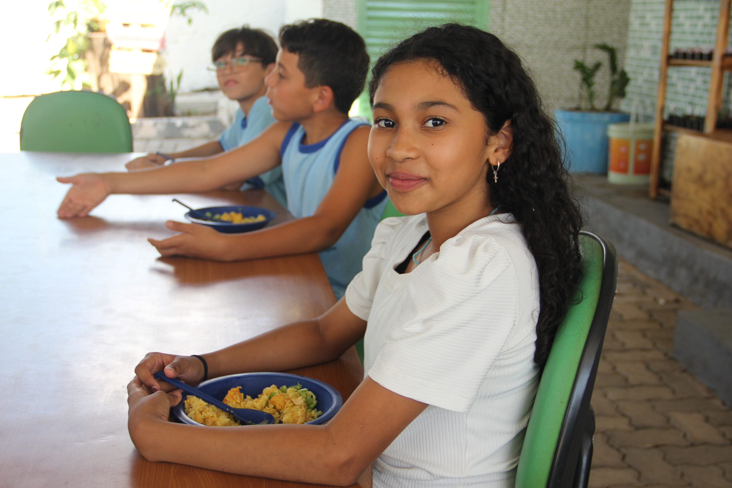 Crianças comendo um prato de galinhada durante o intervalo em uma escola pública brasileira.