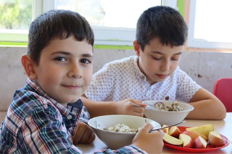 a foto mostra crianças armênias comendo durante o intervalo na escola.