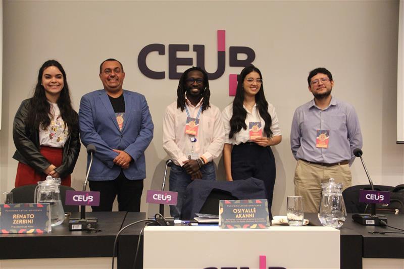 A foto mostra palestrantes convidados em pé no palco do UniCEUB.
