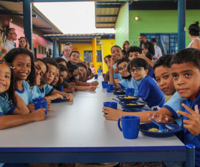 Children in blue uniforms eat their school lunch, consisting of juice and couscous, in a Brazilian public school.