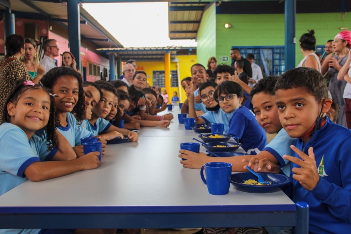 Children in blue uniforms eat their school lunch, consisting of juice and couscous, in a Brazilian public school.